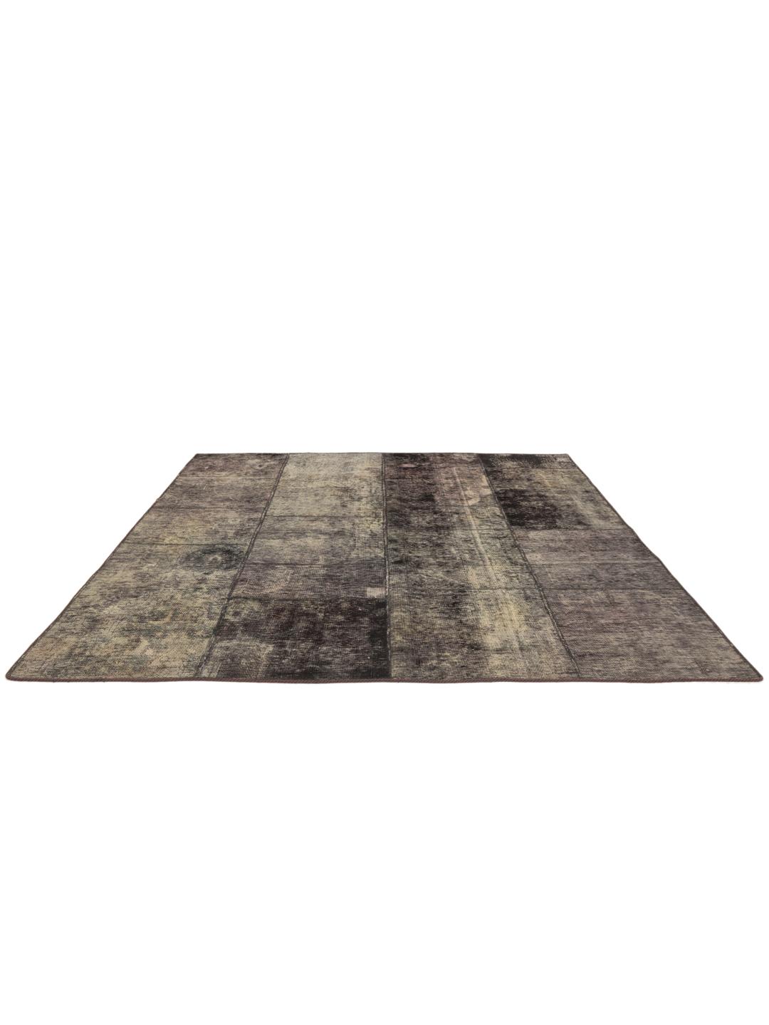 Een vierkant patchwork tapijt met een donkergrijs en houtskoolkleurig kleurenschema met een verweerde, artistieke afwerking.