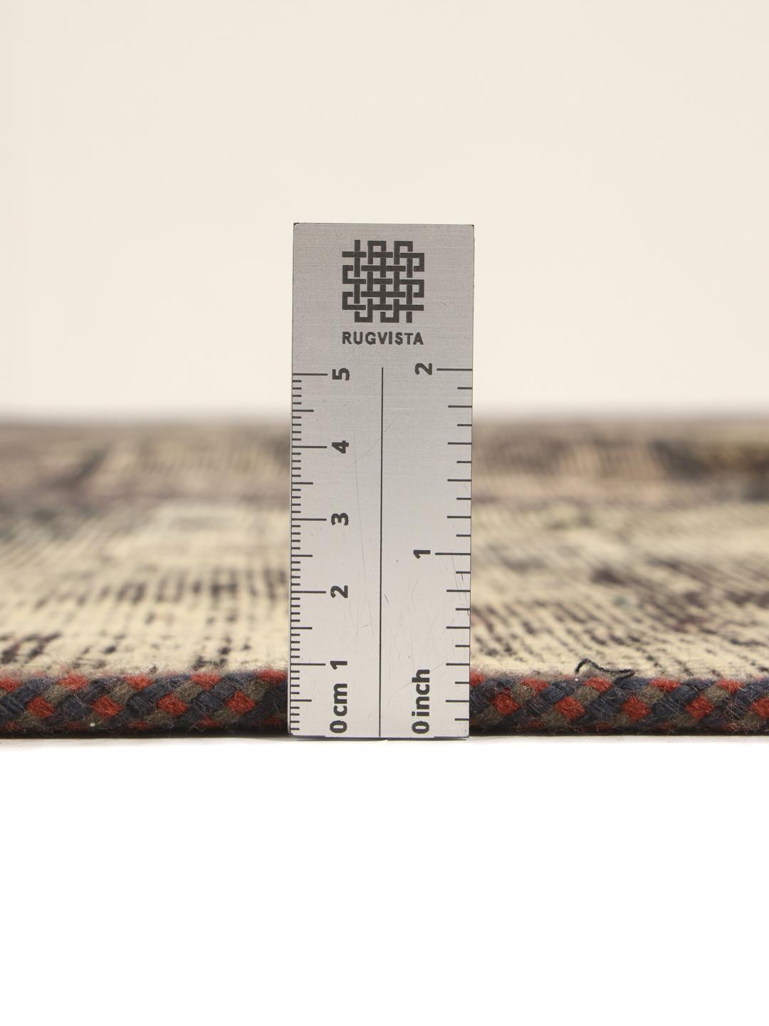 Een vierkant patchwork tapijt met een donkergrijs en houtskoolkleurig kleurenschema met een verweerde, artistieke afwerking.