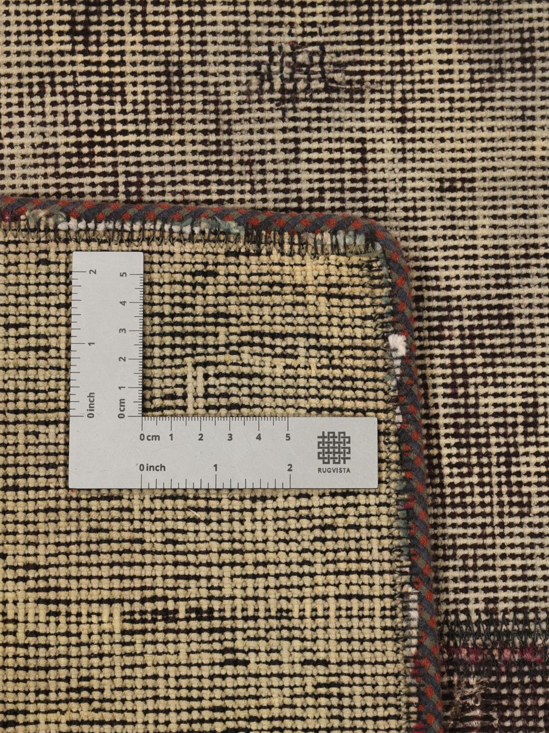Een vierkant patchwork tapijt met een donkergrijs en houtskoolkleurig kleurenschema met een verweerde, artistieke afwerking.