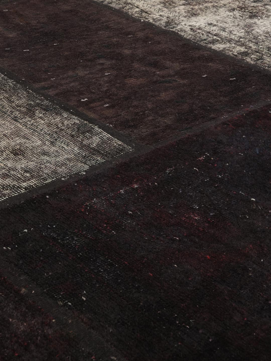 A rectangular patchwork rug from the Middle East featuring a black and grey colour palette.