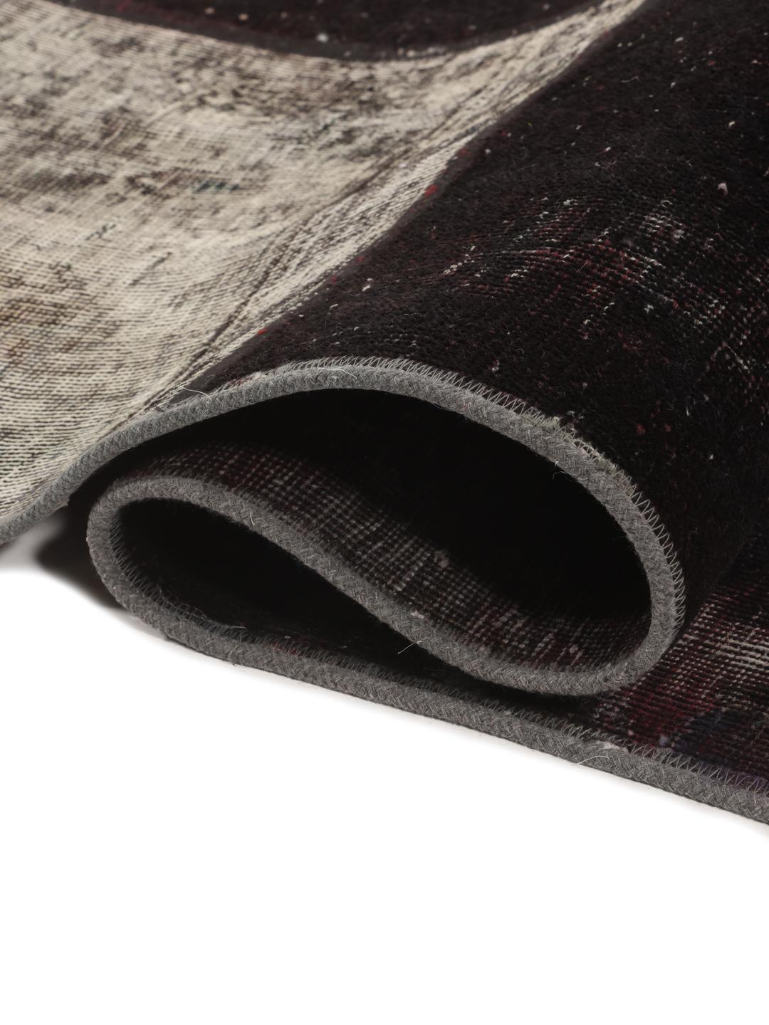 A rectangular patchwork rug from the Middle East featuring a black and grey colour palette.