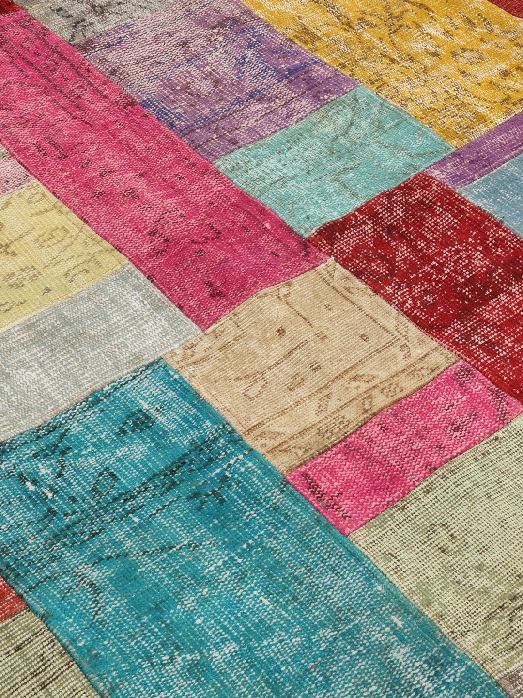 Een groot, levendig, rechthoekig patchwork tapijt uit Turkije met een veelkleurige pool van wol.