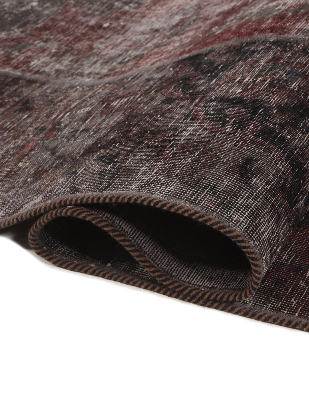 A rectangular patchwork rug featuring vertical stripes in dark-grey and deep red tones, of Middle Eastern origin.