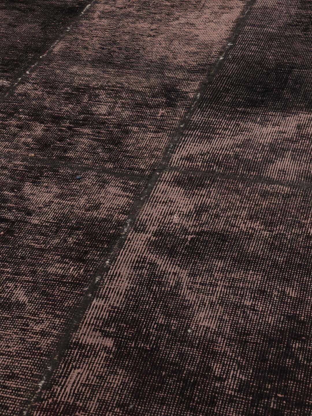 En lang, mørkegrå patchwork-løber med et ornamentalt, falmet mønster.