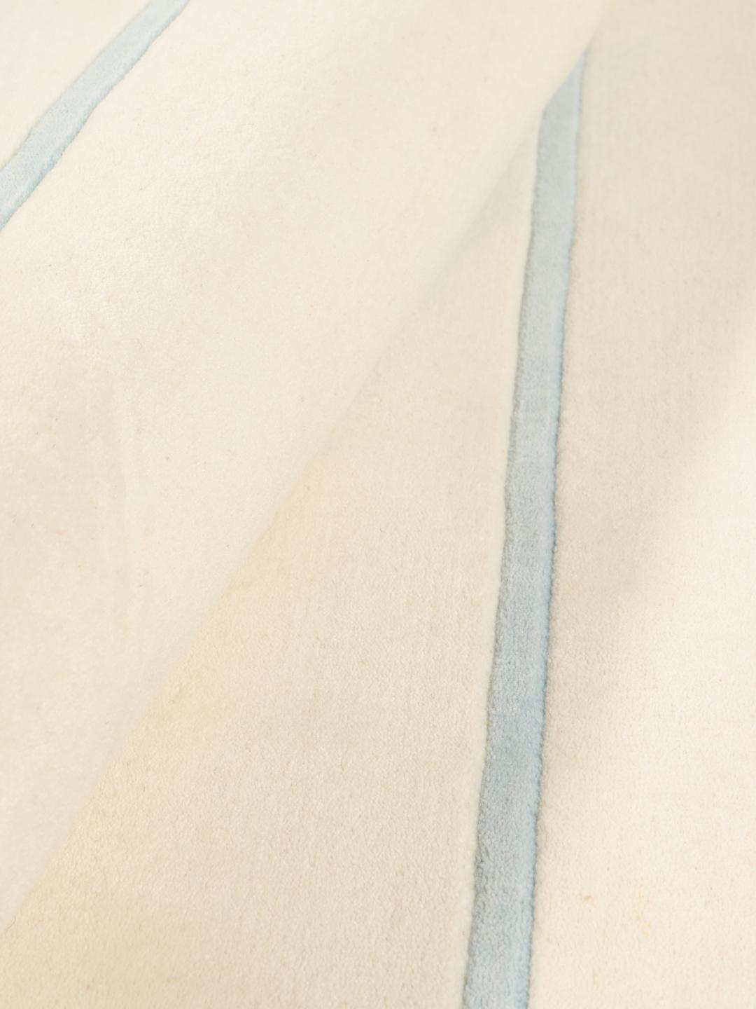 Rundt håndvævet tæppe med minimalistiske linjer fra Indien i beige og lyseblå