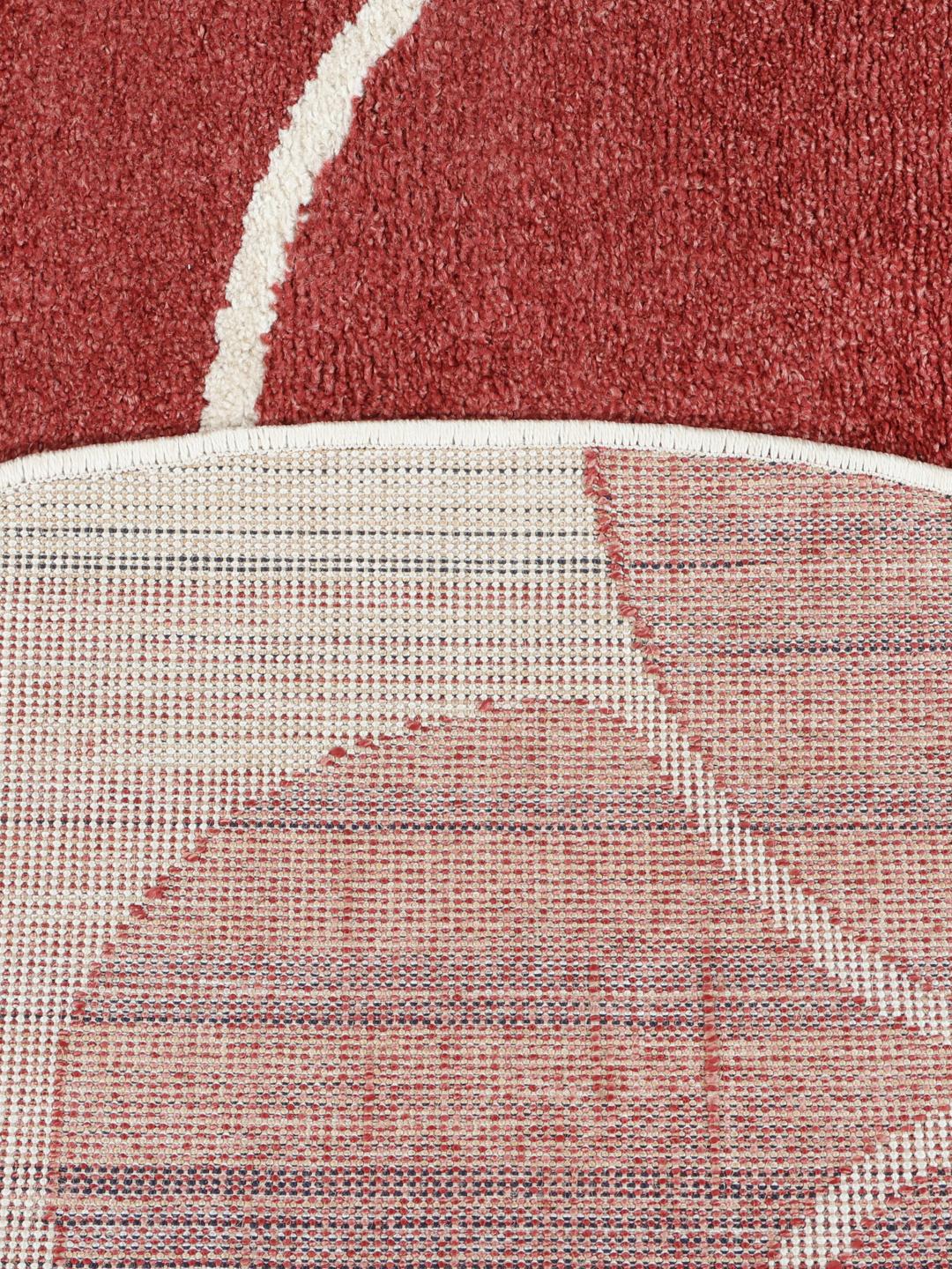 Rond vloerkleed met een donkerrood en gebroken wit bloemenpatroon