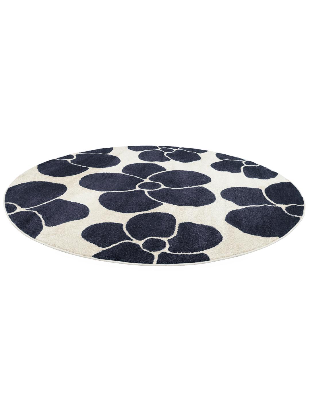 Un tapis rond avec un fond blanc cassé et de grands motifs de fleurs bleu foncé.