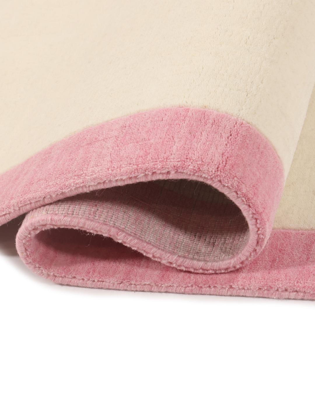 Et minimalistisk håndvævet tæppe fra Indien med beige center og pink kant