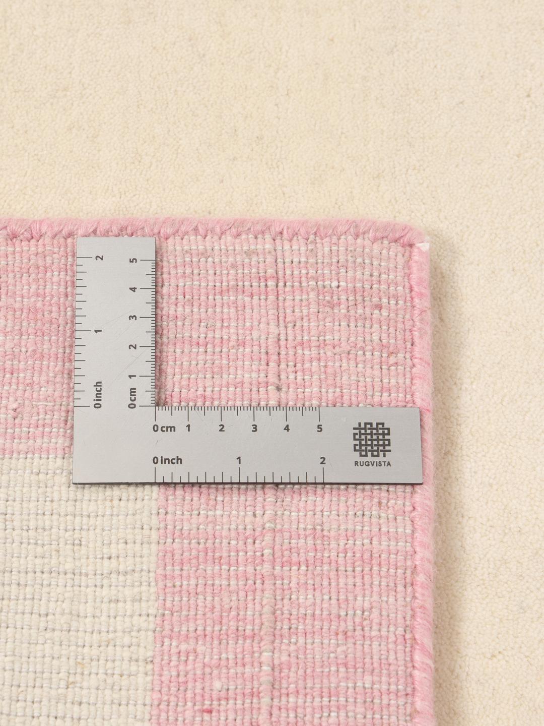 Et minimalistisk håndvævet tæppe fra Indien med beige center og pink kant