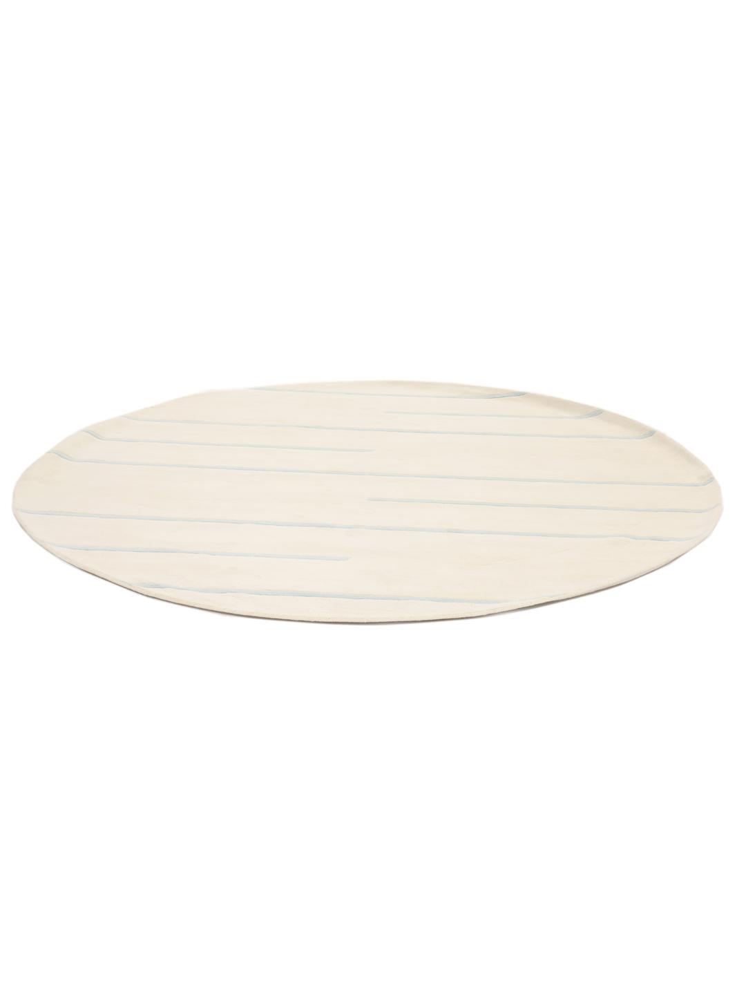 Een rond, beige handgeweven tapijt uit India met lichtblauwe horizontale strepen.
