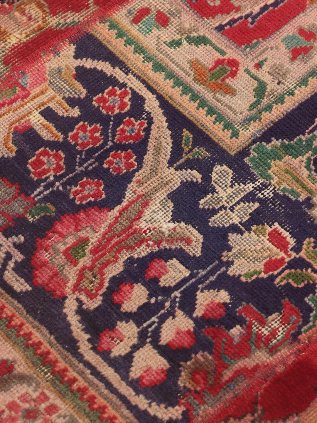 Een levendig rechthoekig patchwork tapijt met ingewikkelde patronen uit het Midden-Oosten in rode en blauwe tinten.