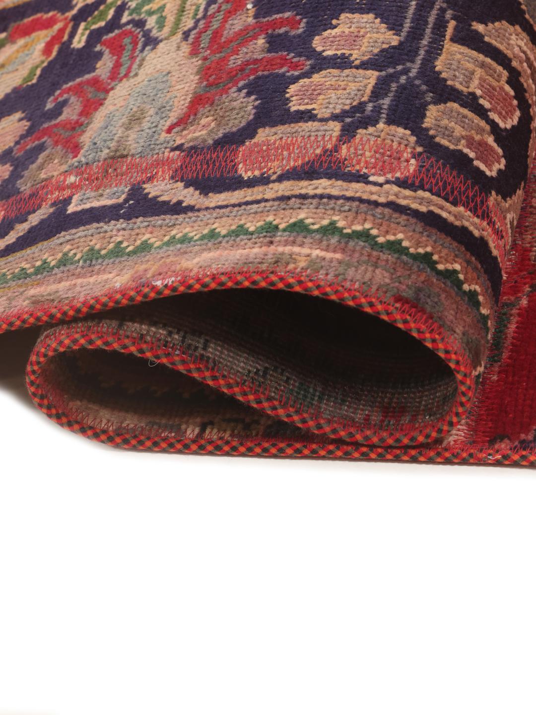 Een levendig rechthoekig patchwork tapijt met ingewikkelde patronen uit het Midden-Oosten in rode en blauwe tinten.