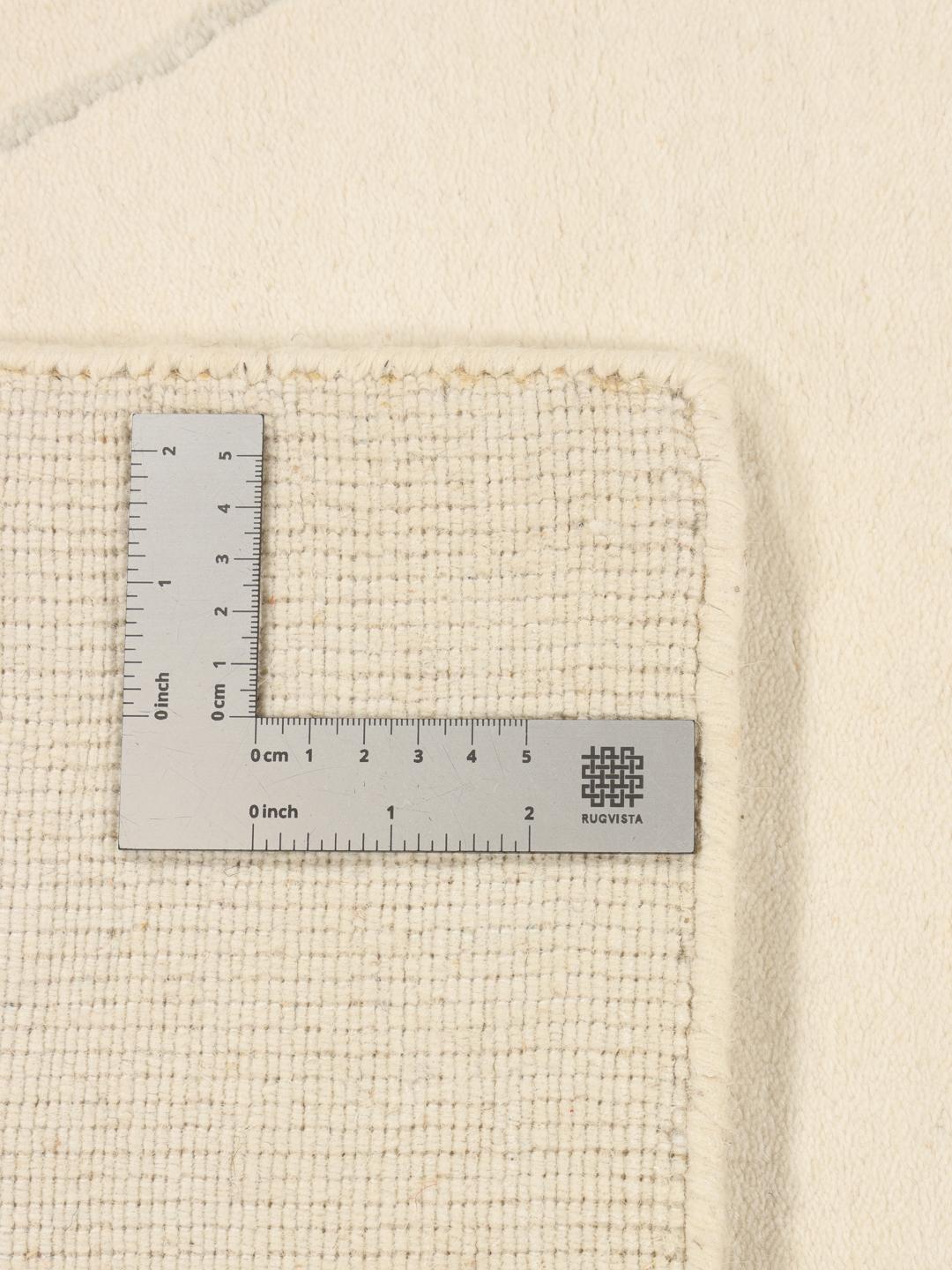 Un tapis moderne fabriqué à la main en Inde avec un motif délicat en losanges beige.