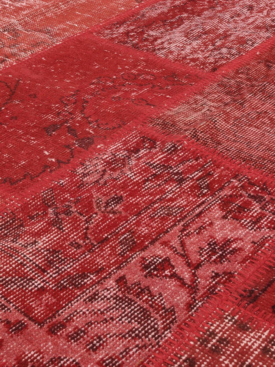 Et rødt, unikt tyrkisk patchwork-teppe med ulike håndknyttede ullteksturer.