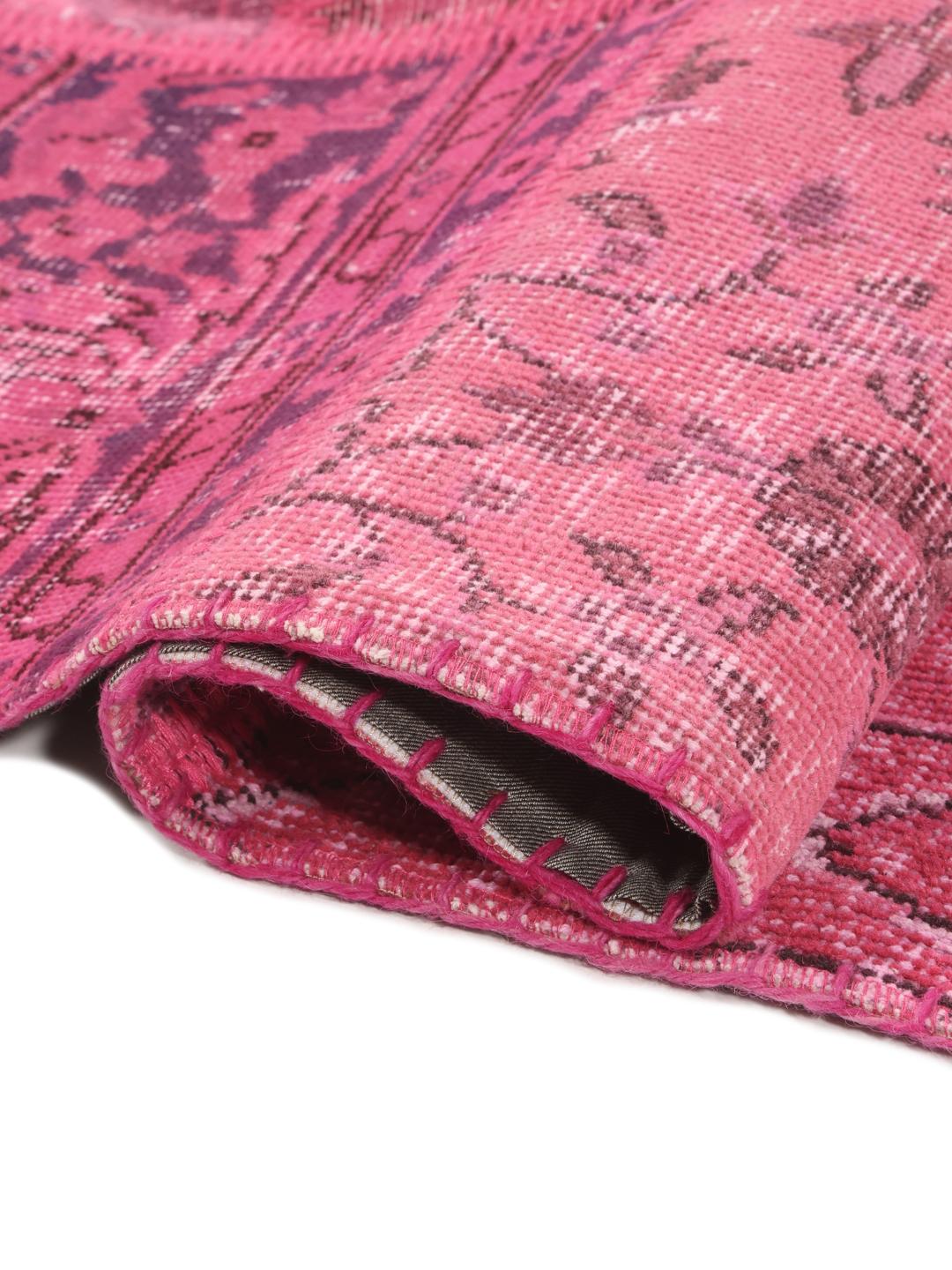 Et levende rosa tyrkisk patchwork-teppe med en rekke tradisjonelle mønstrede fragmenter.