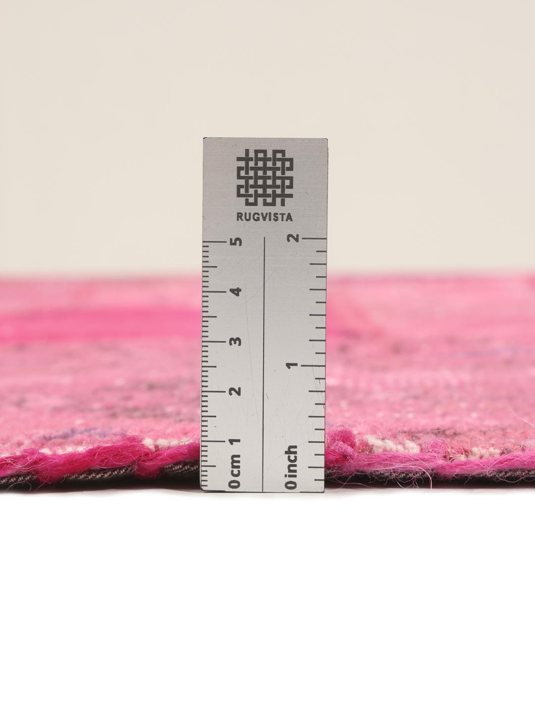 Et levende rosa tyrkisk patchwork-teppe med en rekke tradisjonelle mønstrede fragmenter.