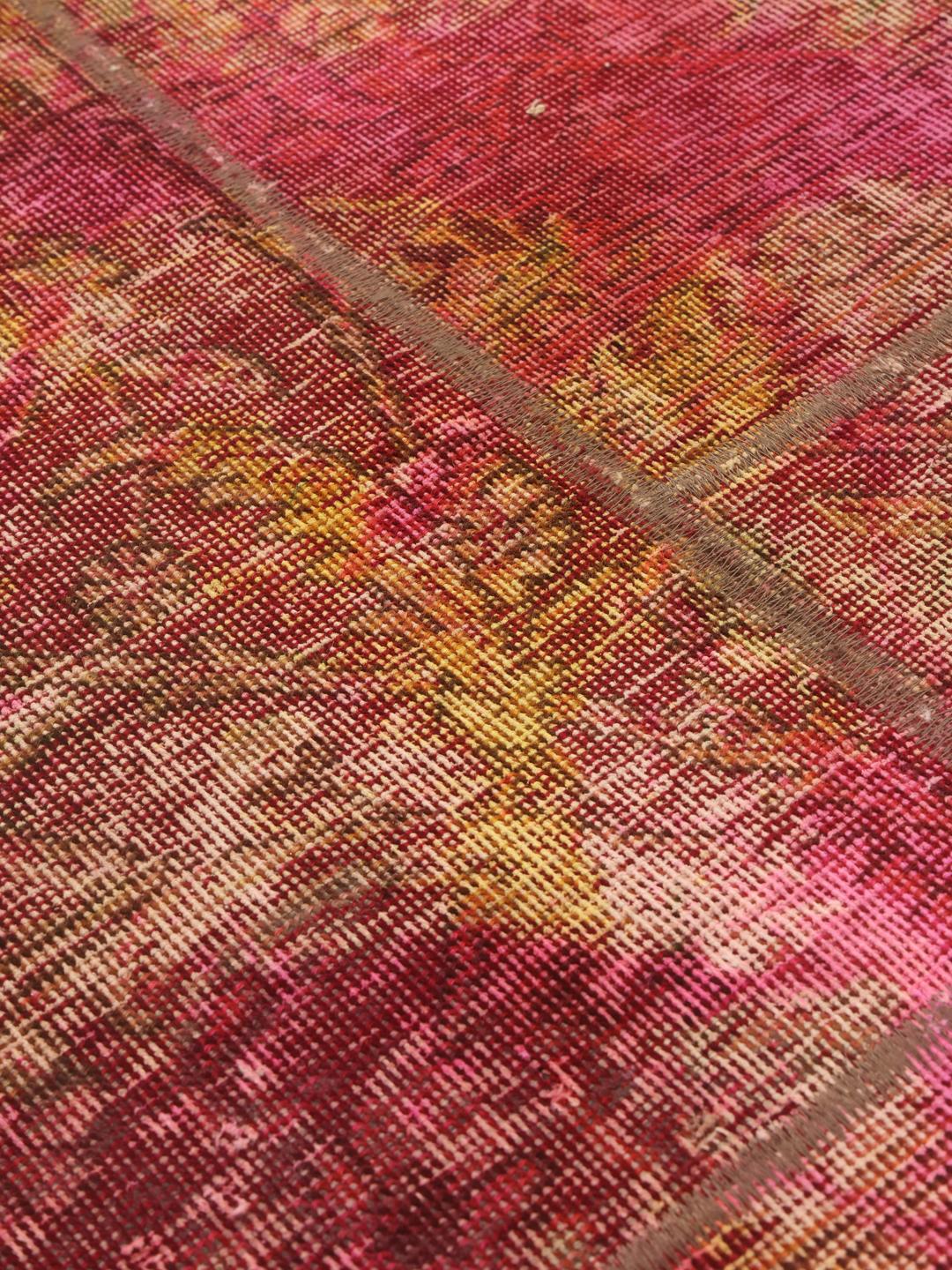 Un tapis patchwork vibrant présentant un mélange de couleurs rouge, jaune et verte provenant du Moyen-Orient