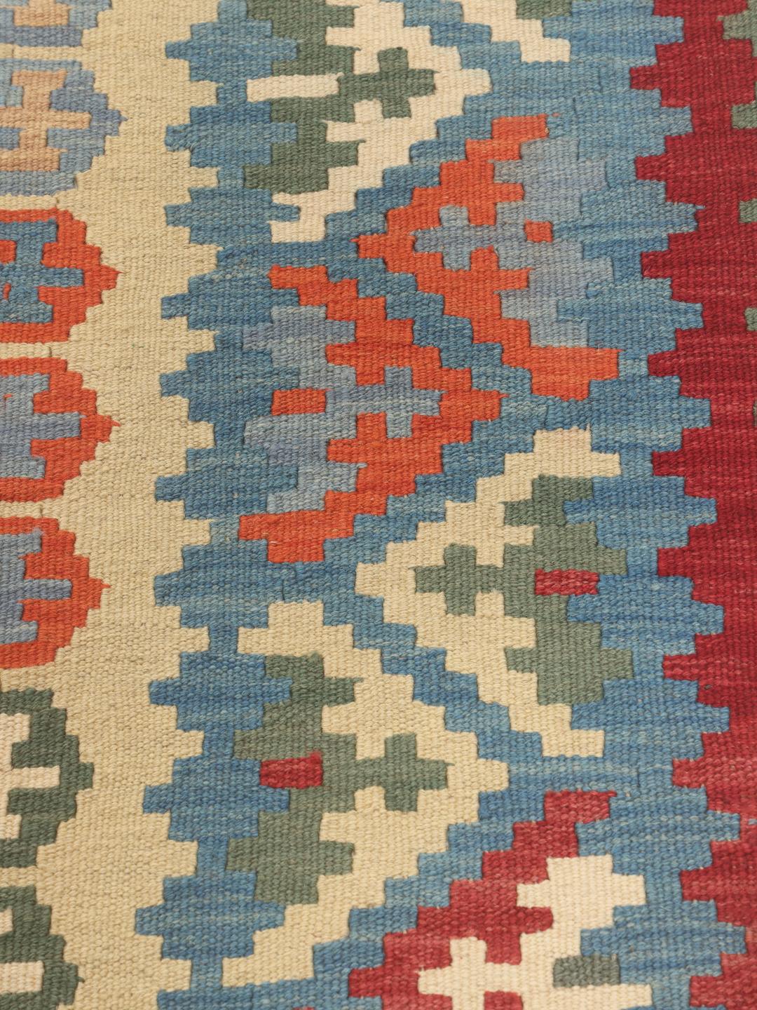 Et stort rektangulært håndvævet Kilim Ghashghai tæppe fra Mellemøsten med et flerfarvet geometrisk mønster.