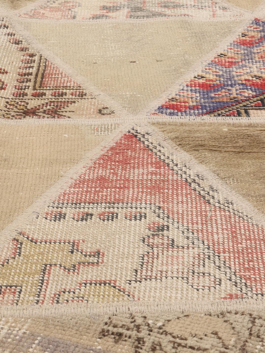 Een uniek Turks patchwork tapijt met een geometrisch driehoekspatroon in veelkleurige wol.