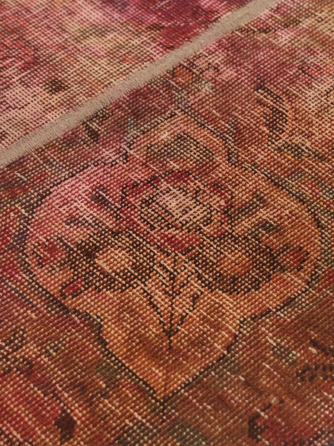 Et rødt og brunt patchwork-tæppe med forskellige vintage-tekstilfragmenter fra Mellemøsten.