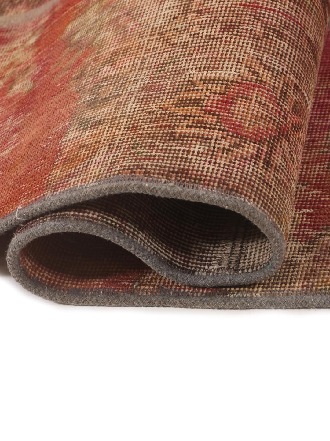 Et rødt og brunt patchwork-tæppe med forskellige vintage-tekstilfragmenter fra Mellemøsten.