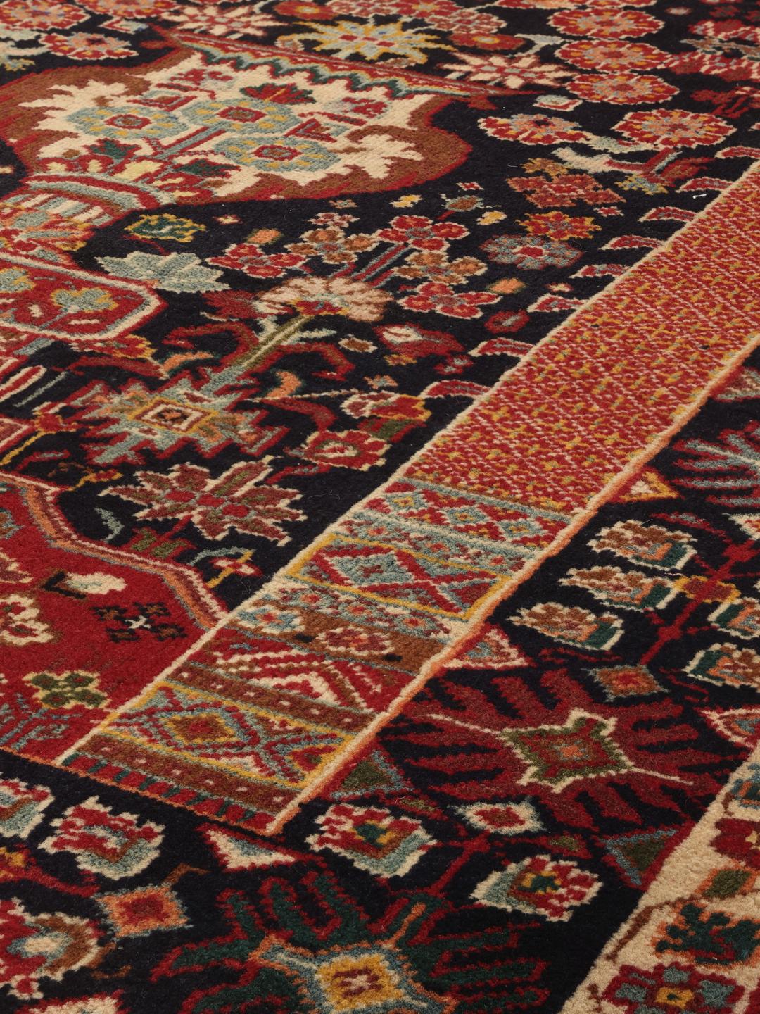 A hand-knotted Qashqai runner featuring traditional tribal motifs in deep red and navy blue.