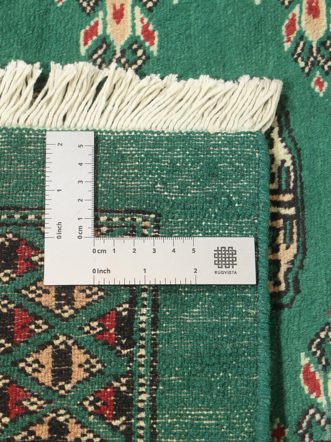 Et håndknyttet Pakistan Bokhara tæppe med en dyb grøn baggrund og traditionelle gentagne motiver
