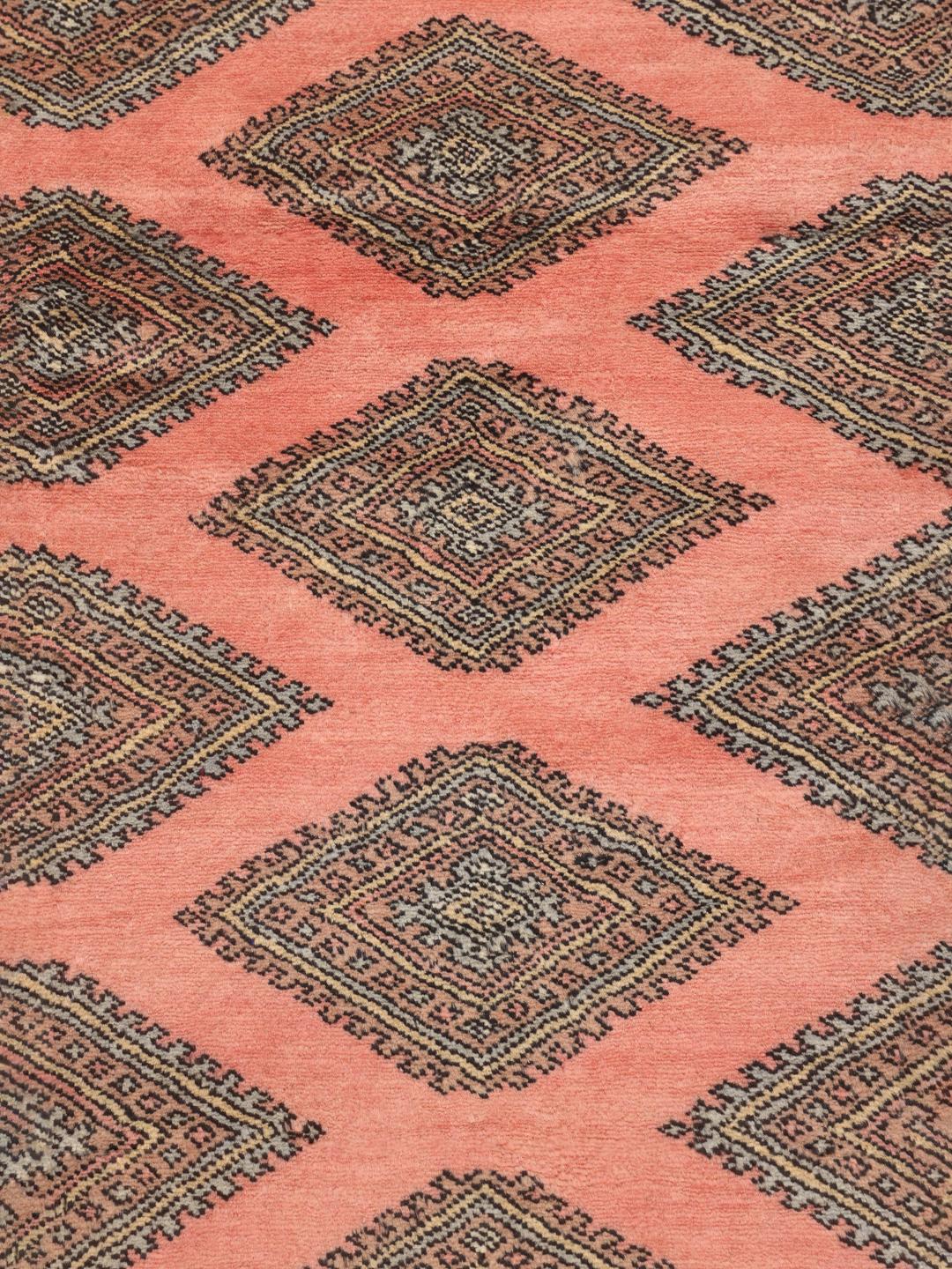 A large hand-knotted Pakistan Bokhara 2ply rug in pink with geometric patterns.