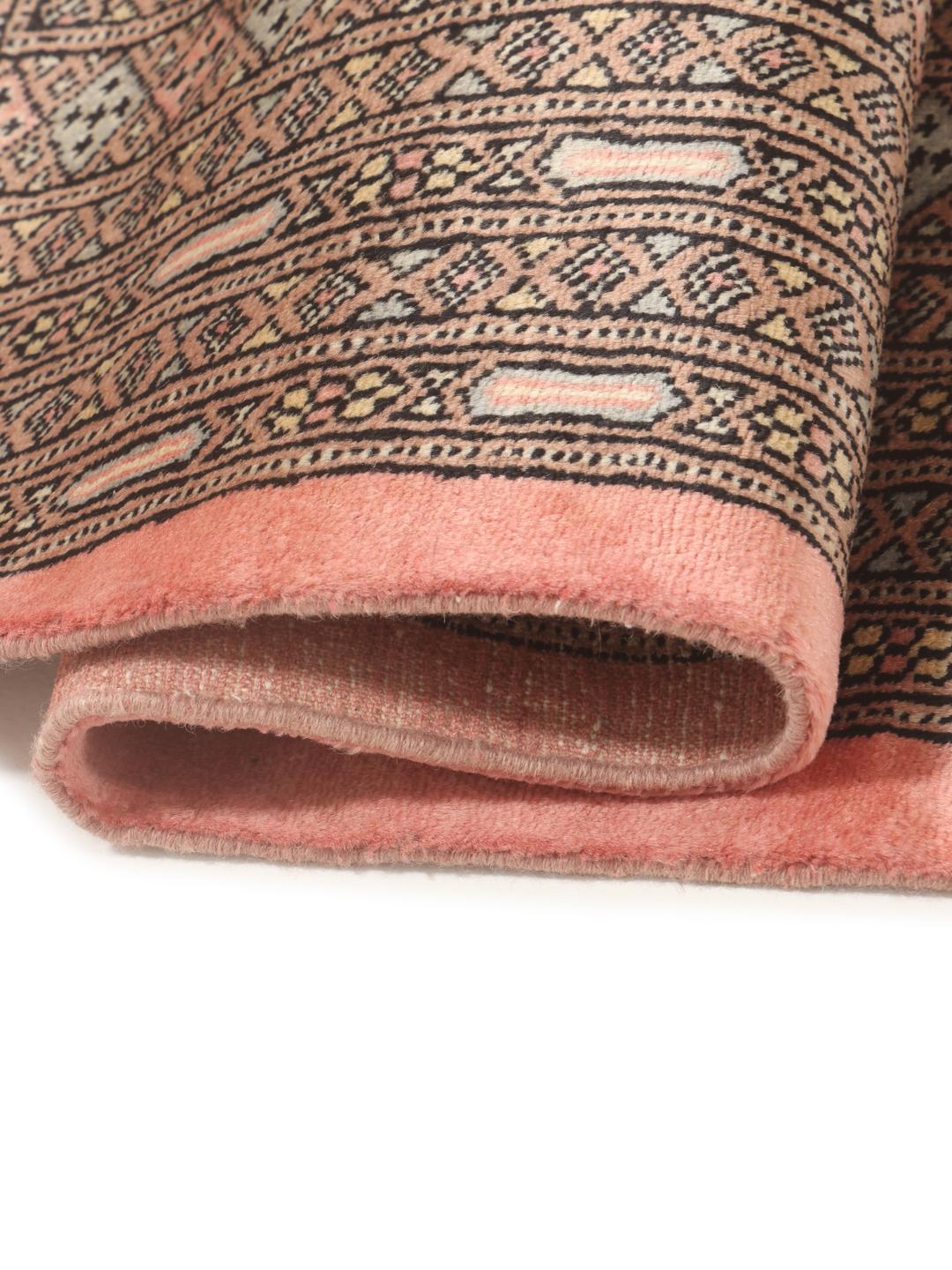 A large hand-knotted Pakistan Bokhara 2ply rug in pink with geometric patterns.