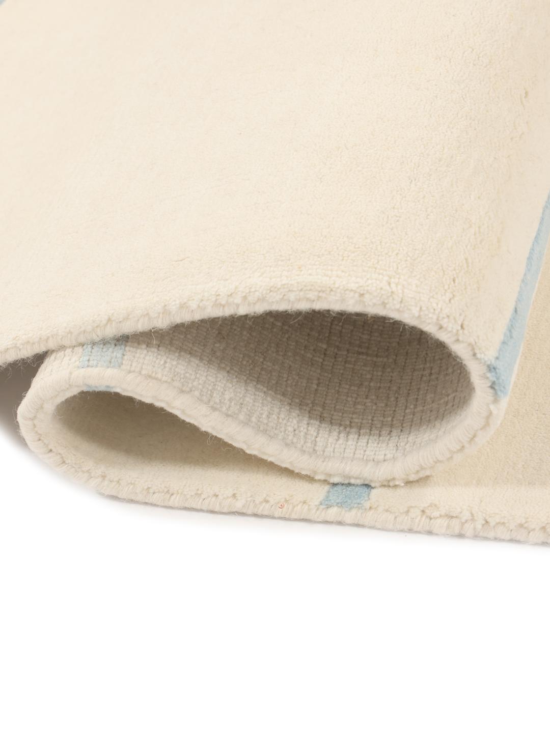 Een minimalistisch handgeweven tapijt uit India met een lichtbeige basis en subtiele blauwe gestreepte accenten.