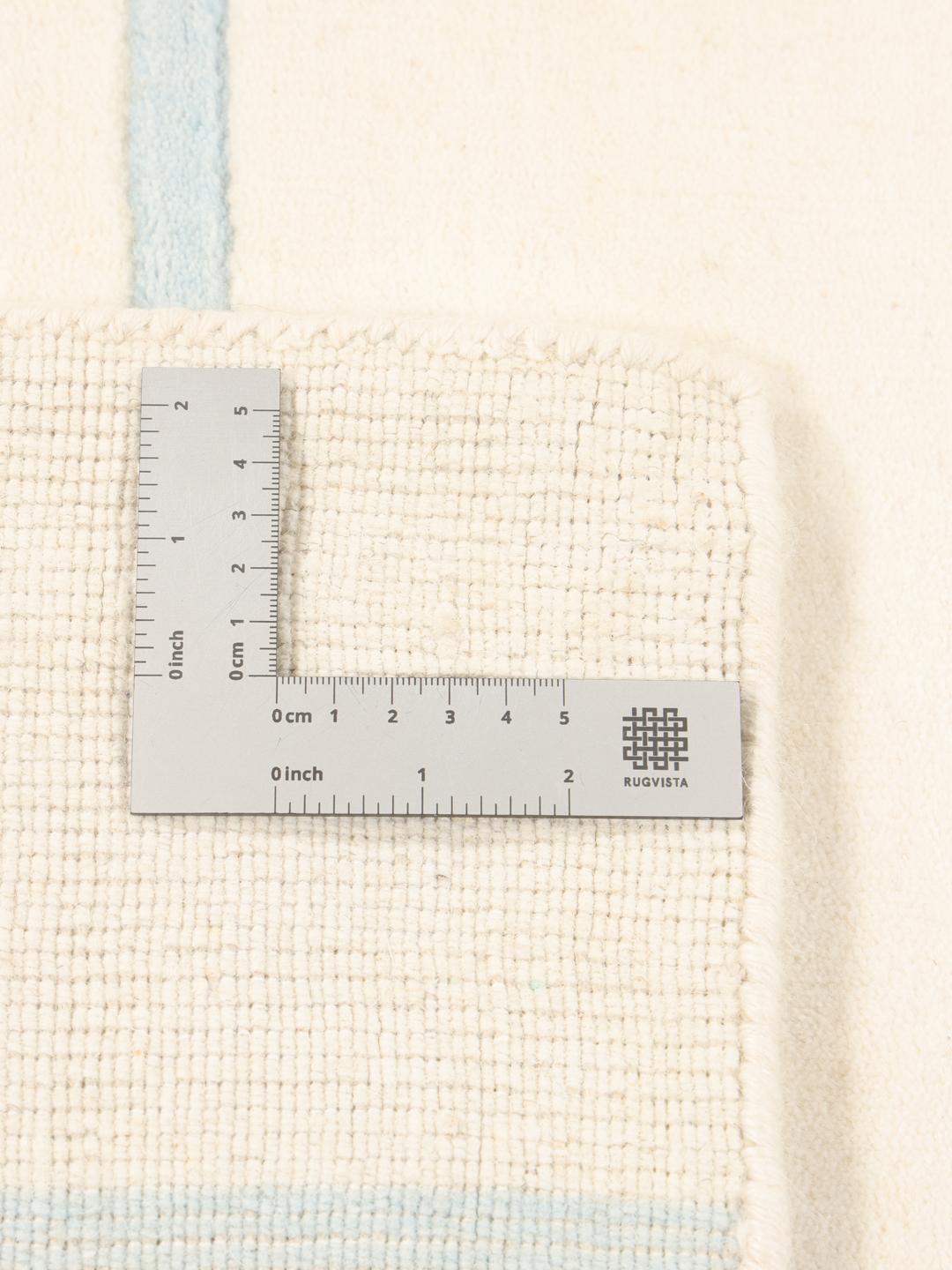 Een minimalistisch handgeweven tapijt uit India met een lichtbeige basis en subtiele blauwe gestreepte accenten.