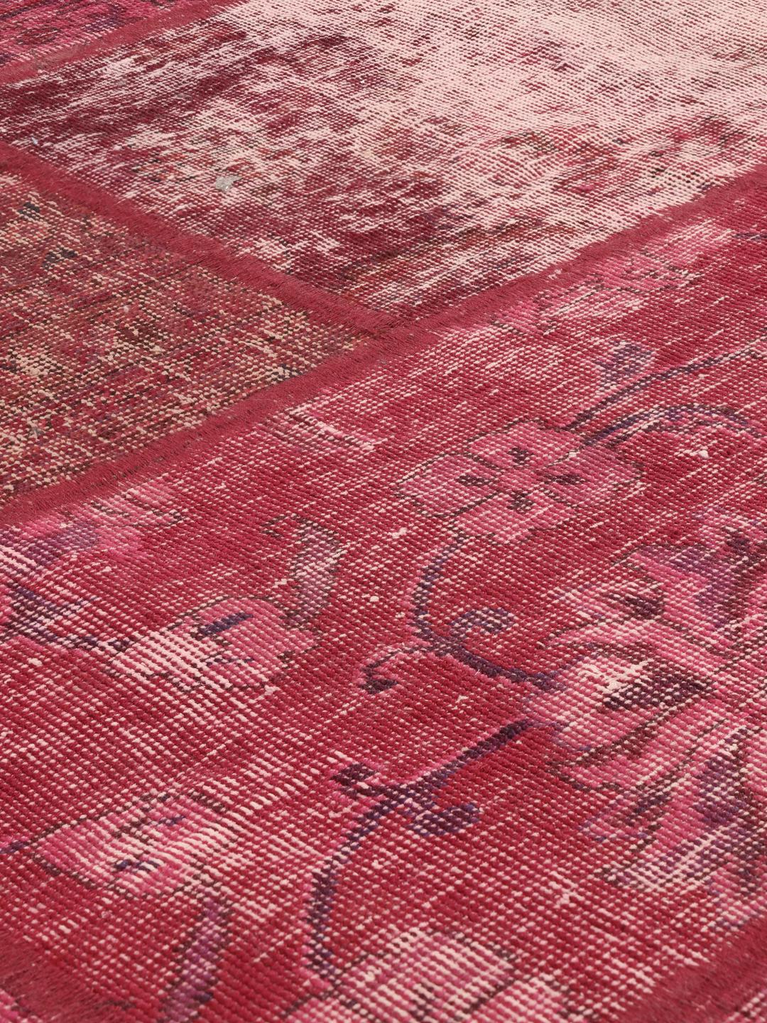 A vibrant patchwork rug from the Middle East featuring diverse shades of dark-red.
