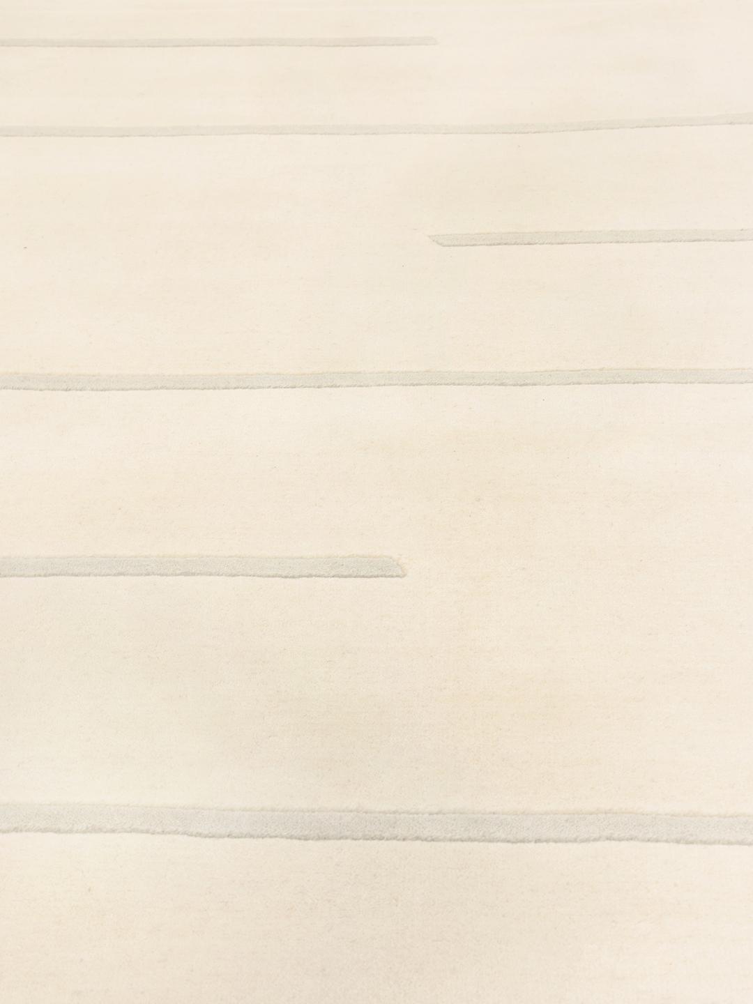 Moderne minimalistisk tæppe med rene linjer i beige, fremstillet i Indien.