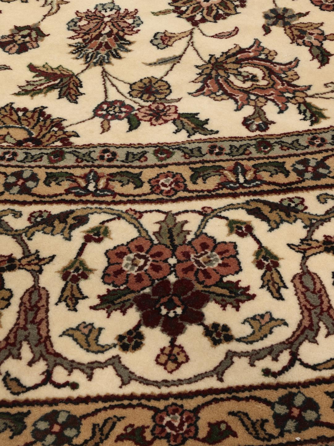 Tapis Sarough rond avec motif floral, noué à la main en Inde dans des tons beige.