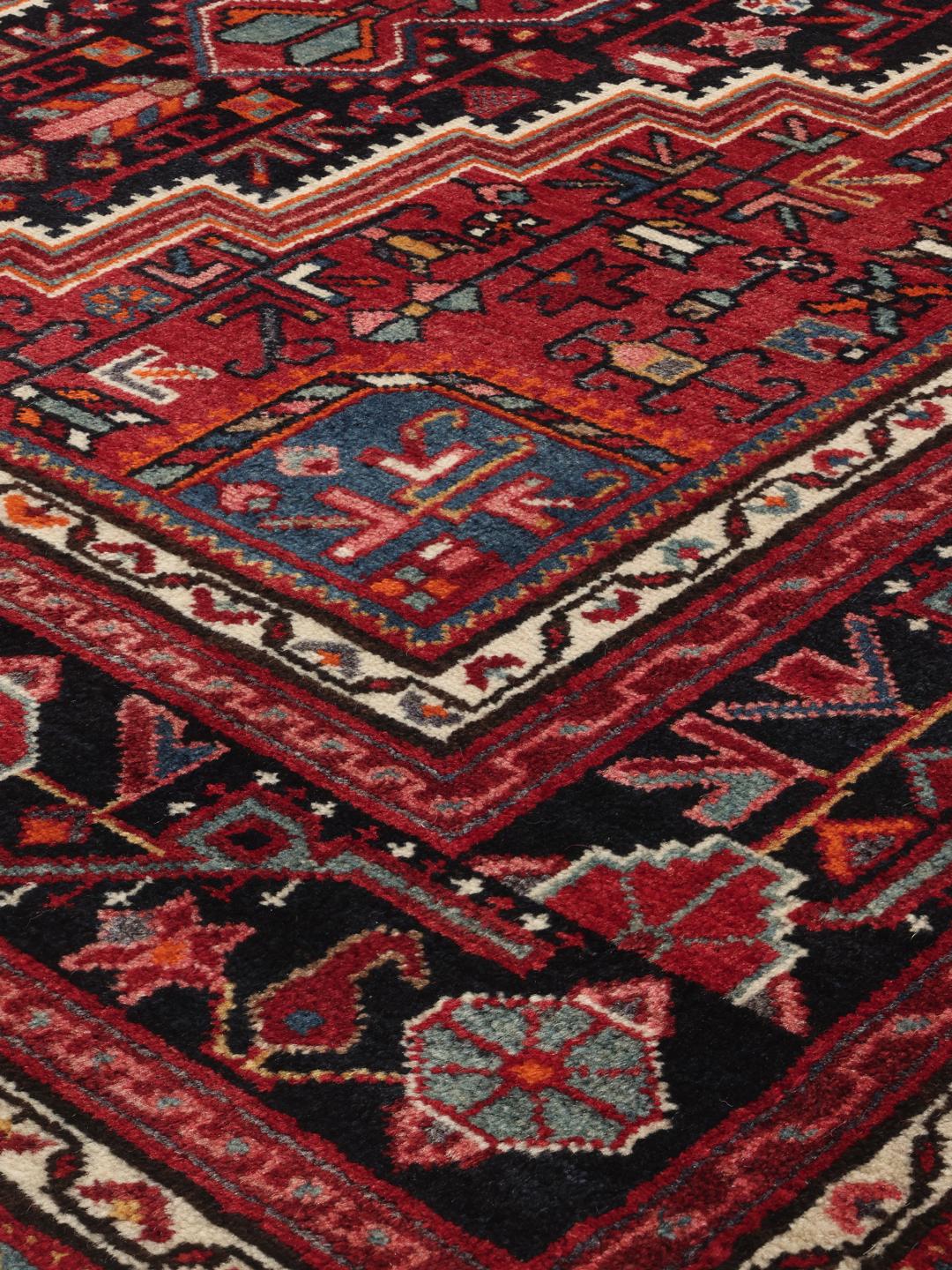 A hand-knotted Toiserkan rug from the Middle East featuring a dark-red and black geometric medallion design.