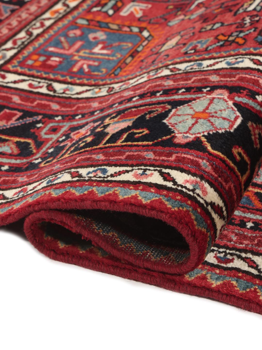 A hand-knotted Toiserkan rug from the Middle East featuring a dark-red and black geometric medallion design.