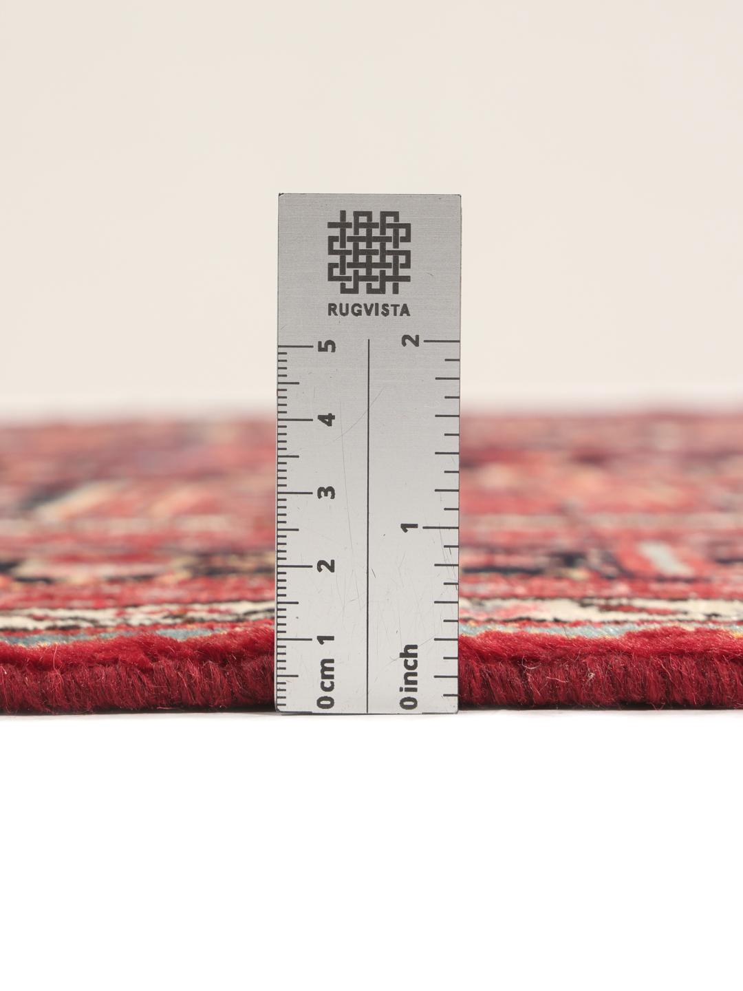 A hand-knotted Toiserkan rug from the Middle East featuring a dark-red and black geometric medallion design.