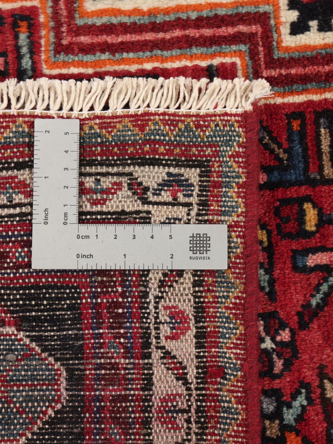 A hand-knotted Toiserkan rug from the Middle East featuring a dark-red and black geometric medallion design.