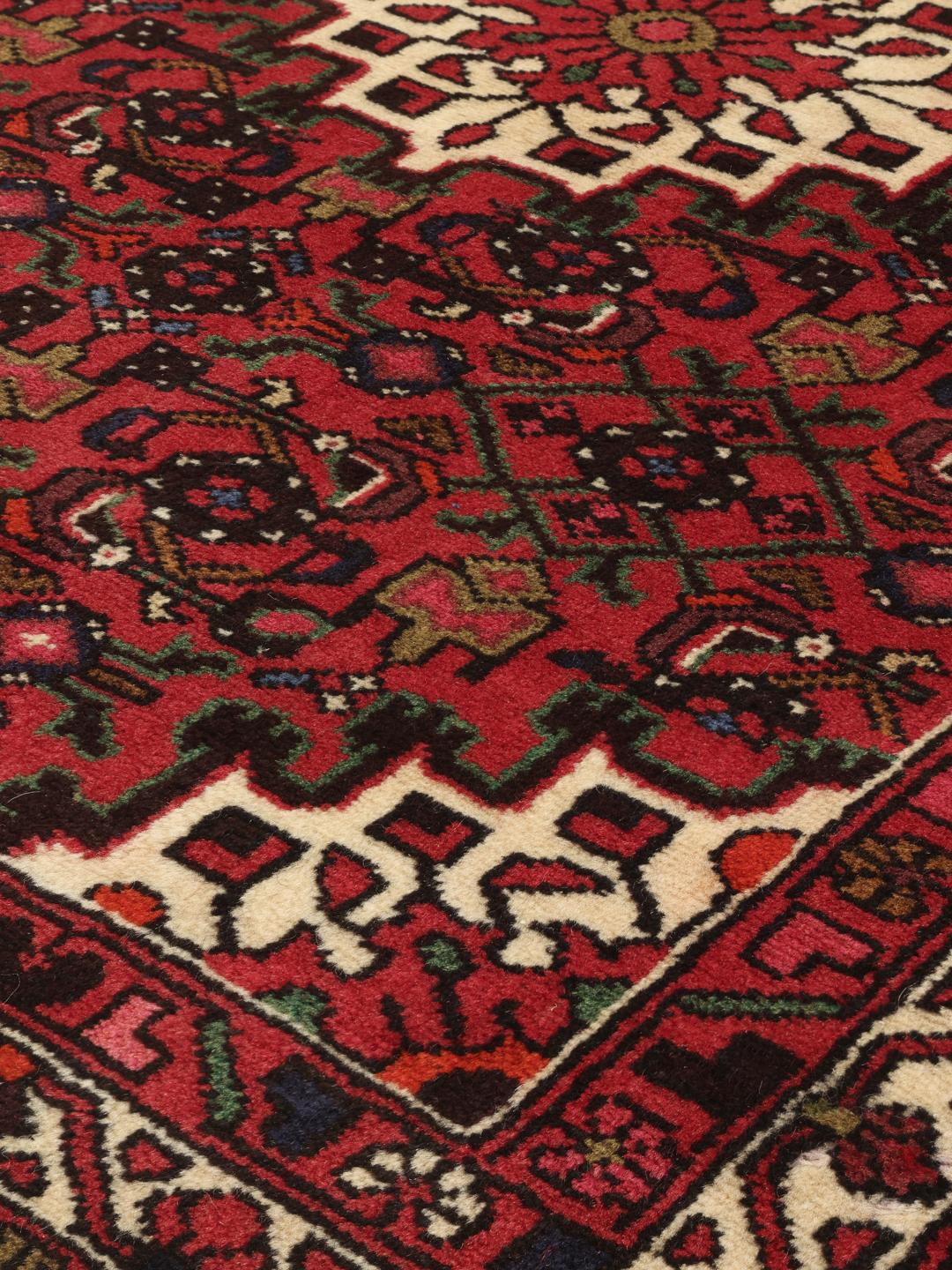 Tapis Hosseinabad noué main en provenance du Moyen-Orient, dans des tons rouge profond avec des motifs géométriques.
