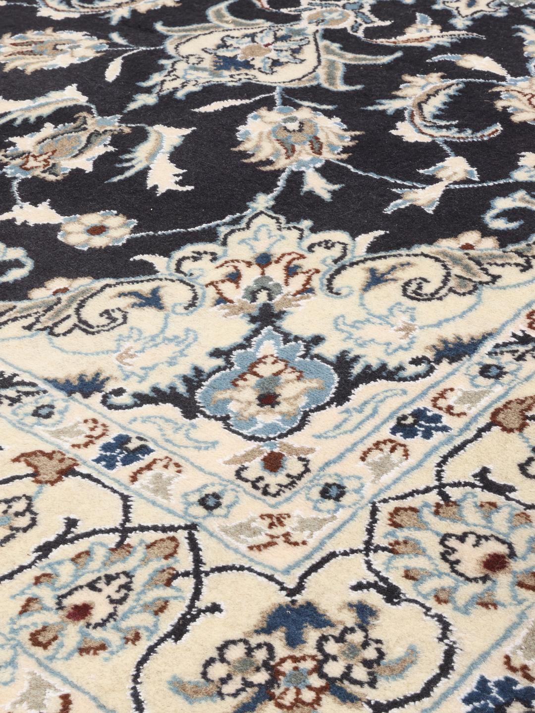 A hand-knotted Nain rug from the Middle East featuring a black field and floral medallion in beige and blue tones.