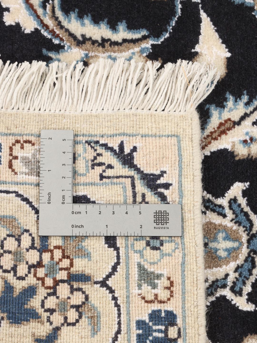 A hand-knotted Nain rug from the Middle East featuring a black field and floral medallion in beige and blue tones.