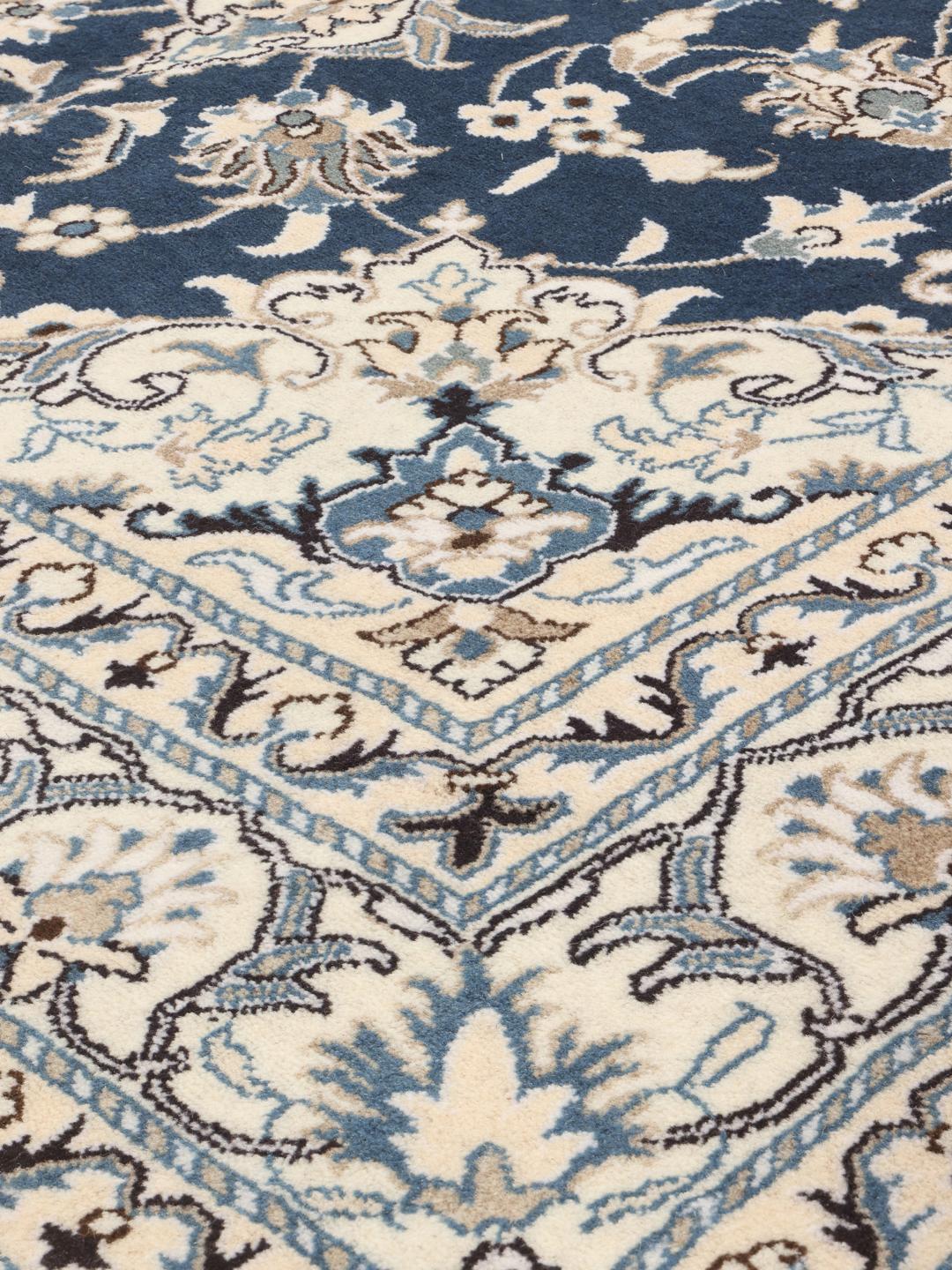 A hand-knotted Nain rug from the Middle East featuring a blue field with ivory floral patterns.