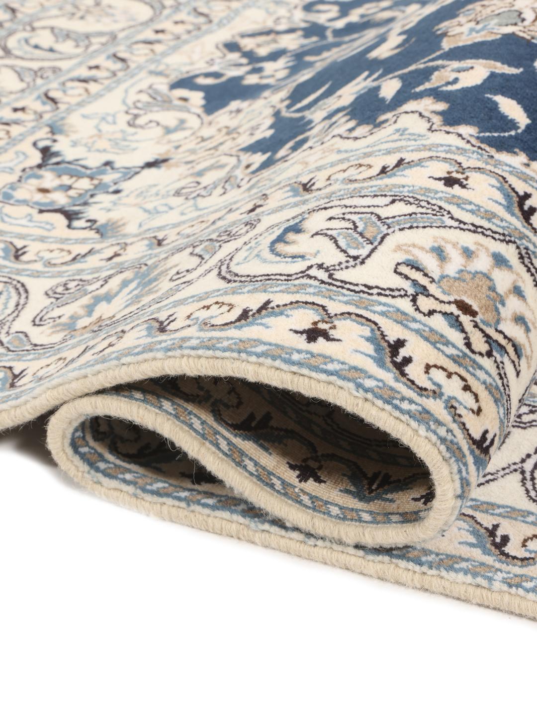 A hand-knotted Nain rug from the Middle East featuring a blue field with ivory floral patterns.