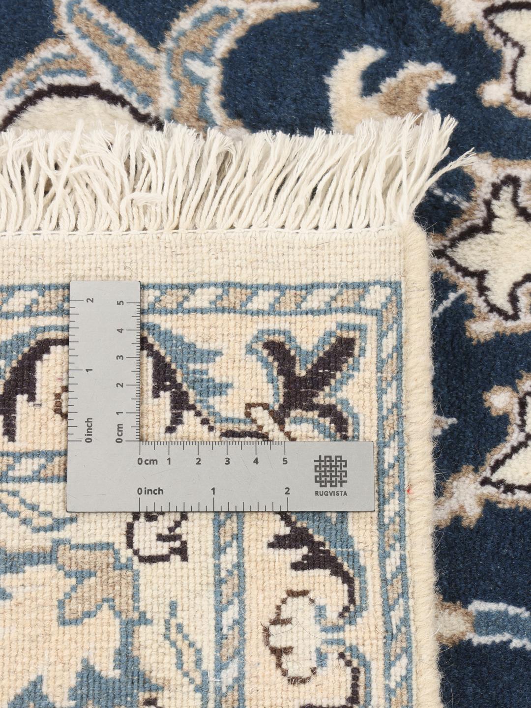 A hand-knotted Nain rug from the Middle East featuring a blue field with ivory floral patterns.