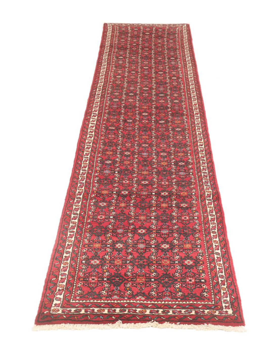 A hand-knotted Middle Eastern runner rug in deep red with intricate geometric patterns.