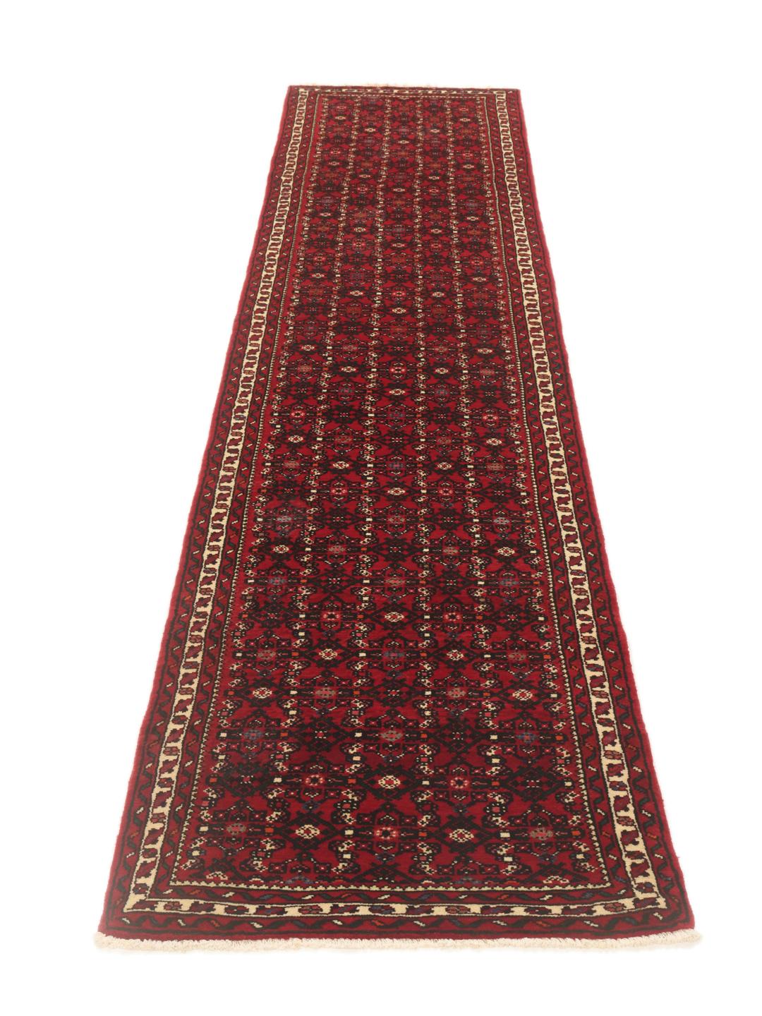 A hand-knotted Middle Eastern runner rug in deep red with intricate geometric patterns.
