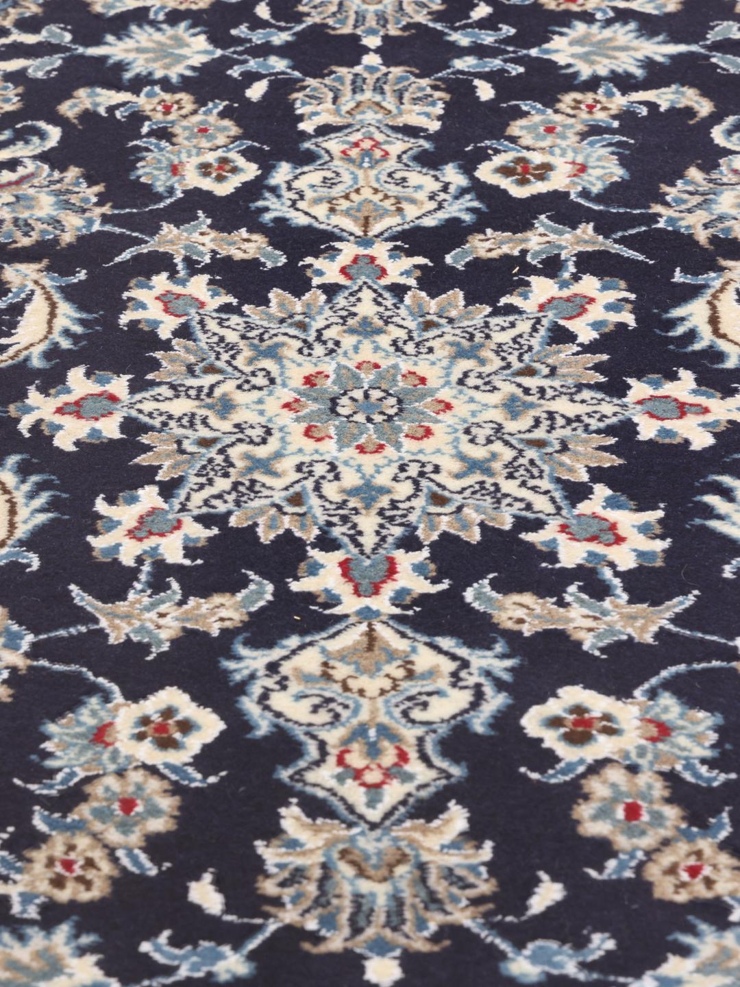 A hand-knotted Nain runner from the Middle East in dark blue with floral patterns.