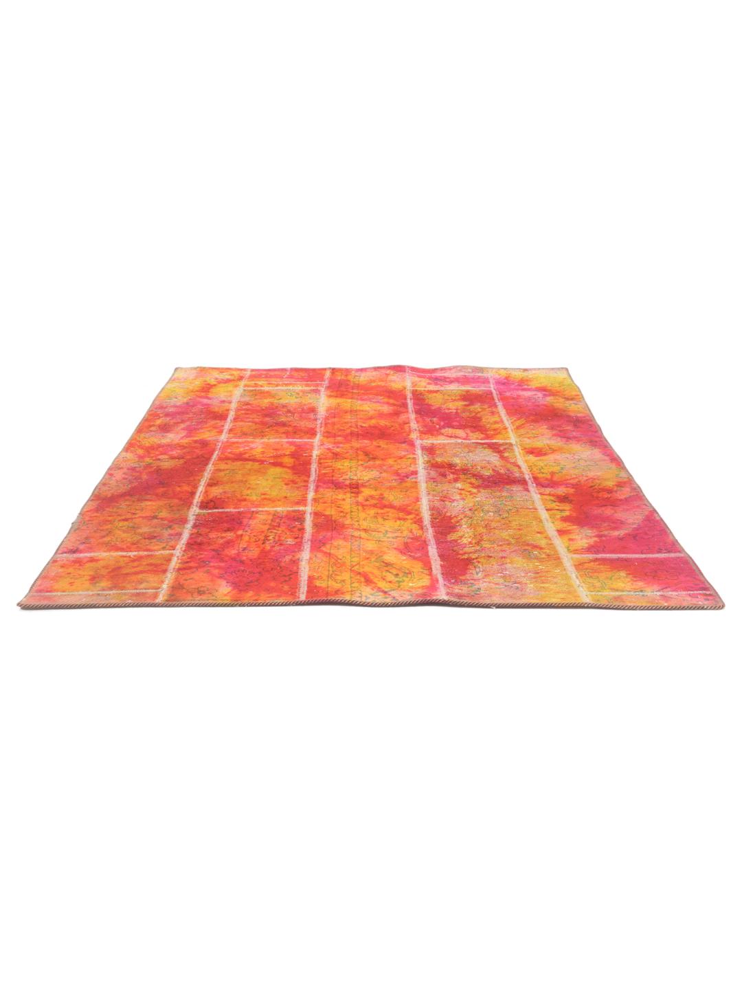 Un tapis patchwork rectangulaire vibrant provenant du Moyen-Orient, présentant un mélange de motifs floraux rouges et orange.