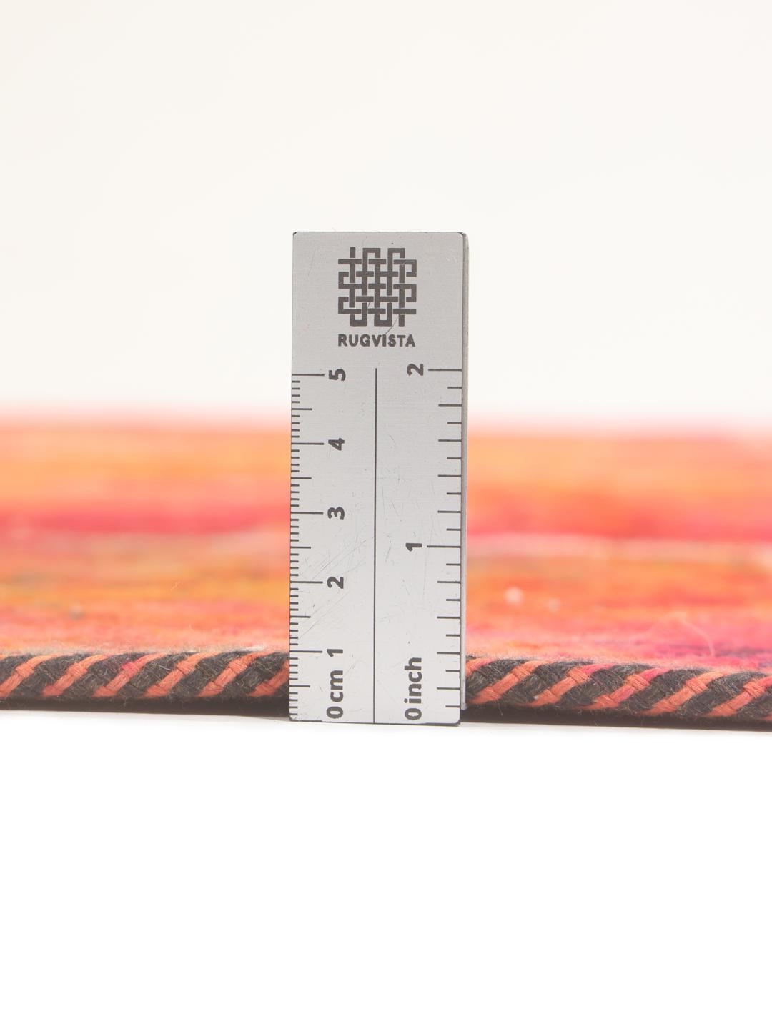 Un tapis patchwork rectangulaire vibrant provenant du Moyen-Orient, présentant un mélange de motifs floraux rouges et orange.
