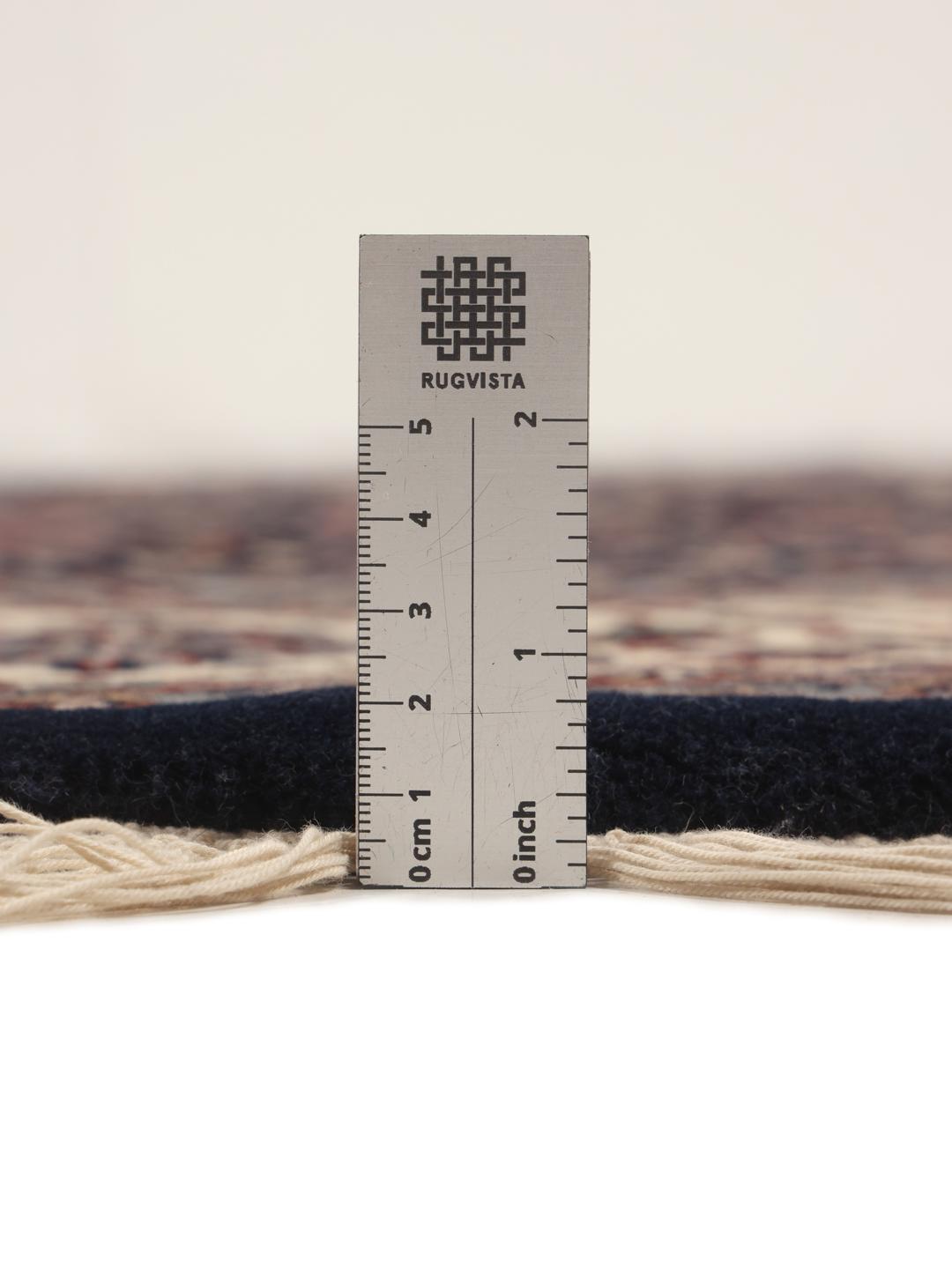 Rond handgeknoopt tapijt uit India met bloemmotieven in zwart en beige.